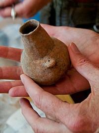 hands holding a small clay pot hands holding a small clay pot