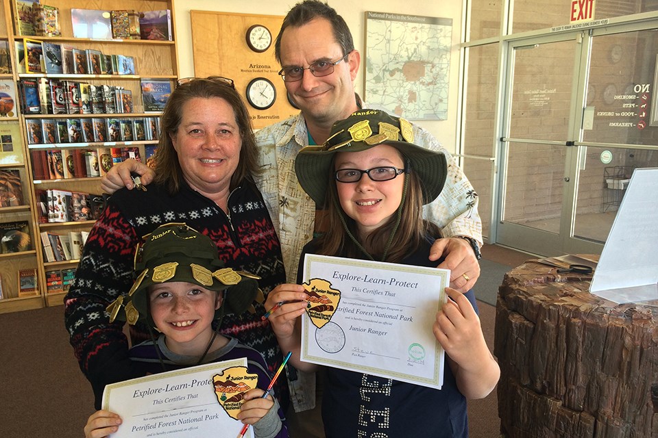 Two kids and their family show off their junior ranger certificates and badges Two kids and their family show off their junior ranger certificates and badges