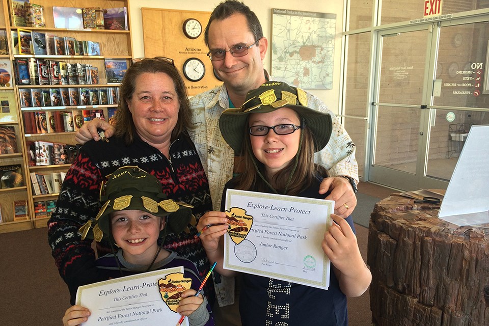 Two kids and their family show off their junior ranger certificates and badges