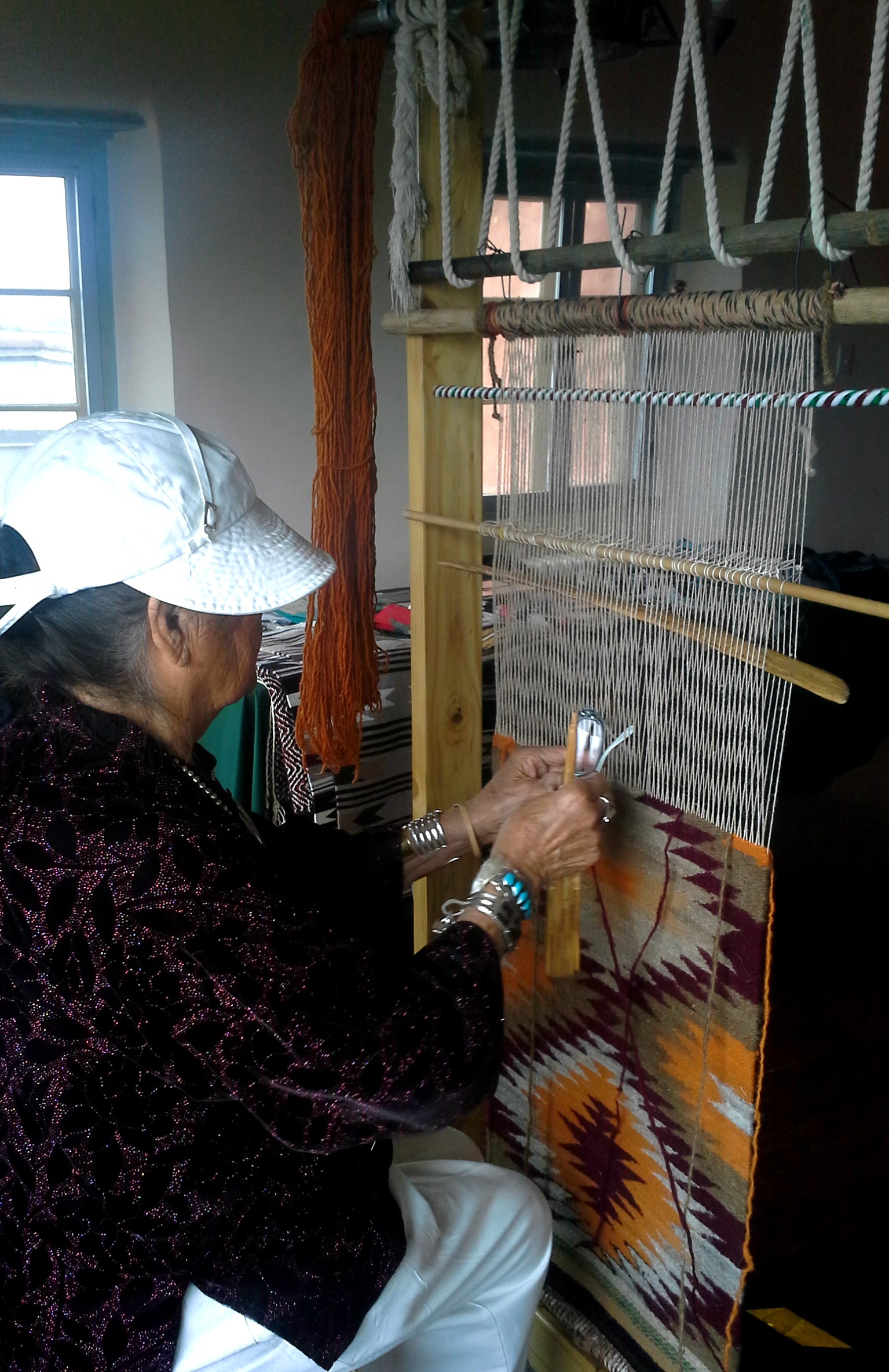 Lucille Smith weaving a rug on a tradition Diné loom