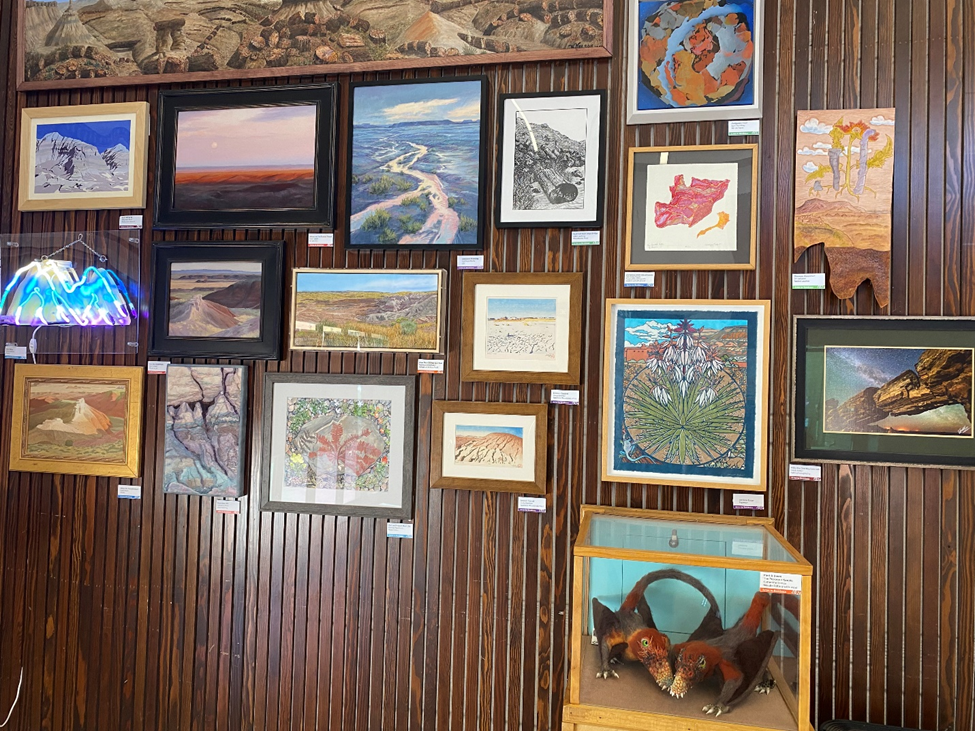 Multiple framed artwork on a dark wood paneled wall. Multiple framed artwork on a dark wood paneled wall.