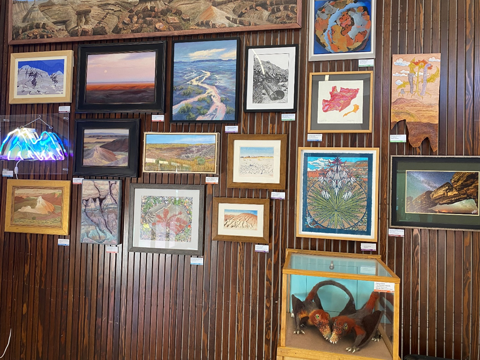 Multiple framed artwork on a dark wood paneled wall.