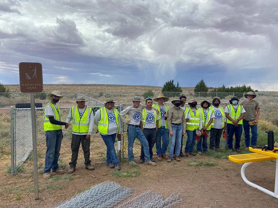 Youth Conservation Corps participants standing in front of the chainlink fence surrounding the new dog park.