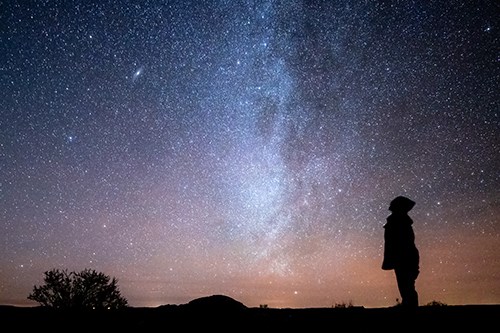 Person silhouetted against a dark stary sky