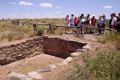 Visitors looking into the kiva at Puerco Pueblo