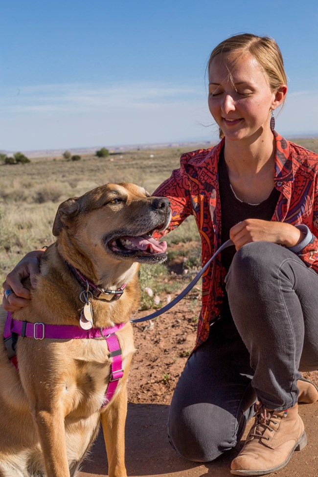 A young woman pets a happy doggo. A young woman pets a happy doggo.