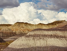 puffy clouds over badlands with distinct banding
