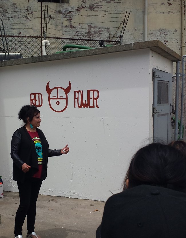 Dr. Warjack helped re-paint "red power" sign on Alcatraz Island, seen here in June 2016. Dr. Warjack standing next to a spray painted building with the words "Red Power".
