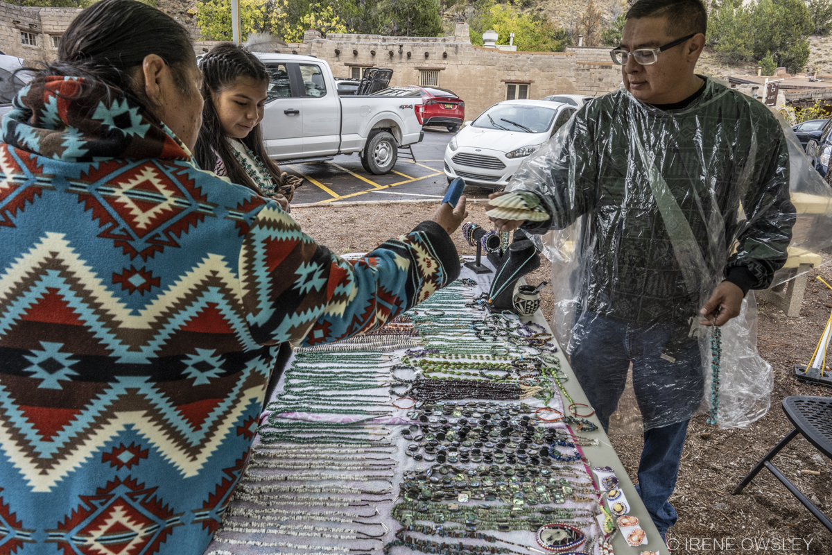 Bandelier Fall Fiesta '22 3 people stand over a table filled with local Pueblo Jewelry