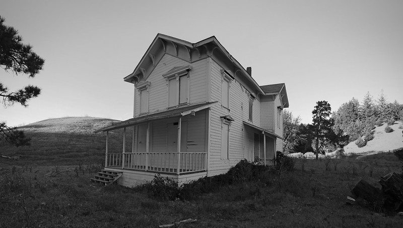 White victorian two story house in the middle of grassy field by Jeff Boyd