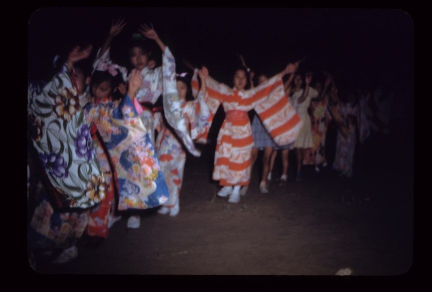 A line of young girls holding their hands up in the air while wearing colorful kimonos. A line of young girls holding their hands up in the air while wearing colorful kimonos.