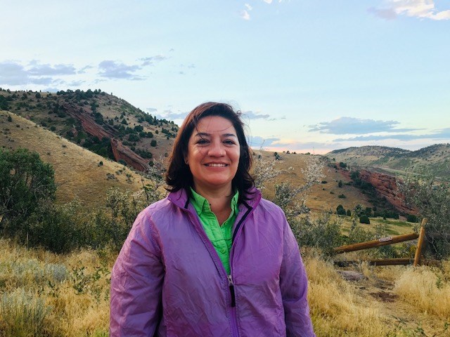 A photograph of Maite Arce smiling for the camera.