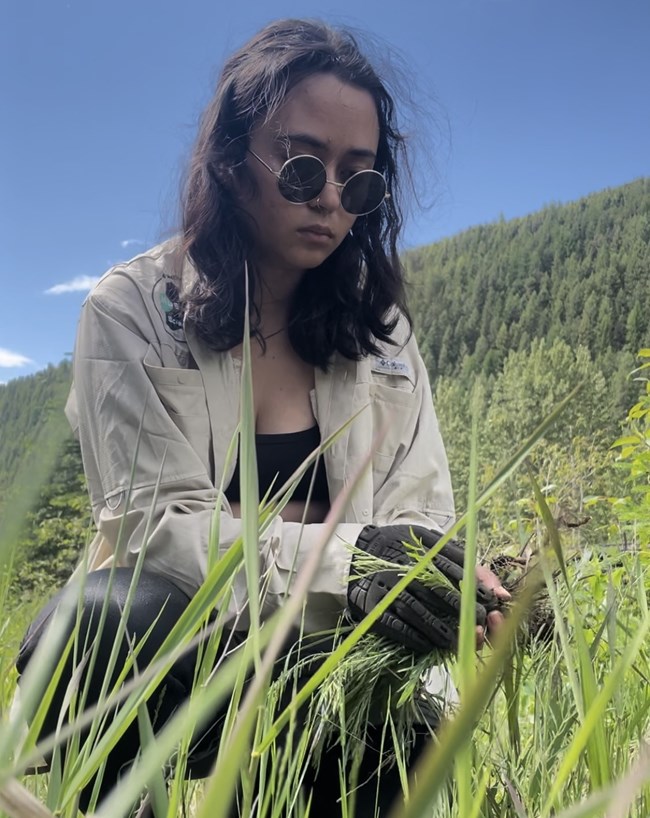 A young woman kneels in the grass