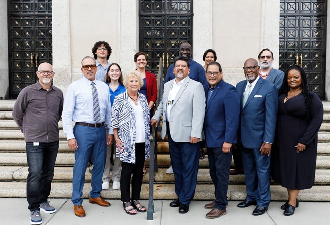 A group of individuals in business attire standing on white stairs