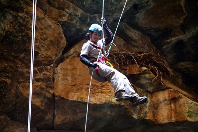 An image of Julie Meachen inside a cave and rappelling to an excavation site.