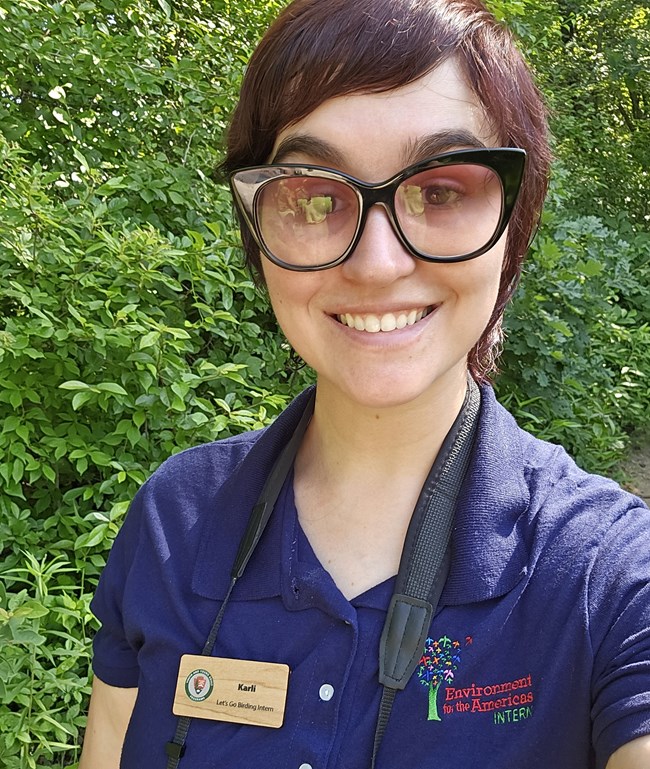 A young woman wears a blue shirt that reads "Environment for the Americas"