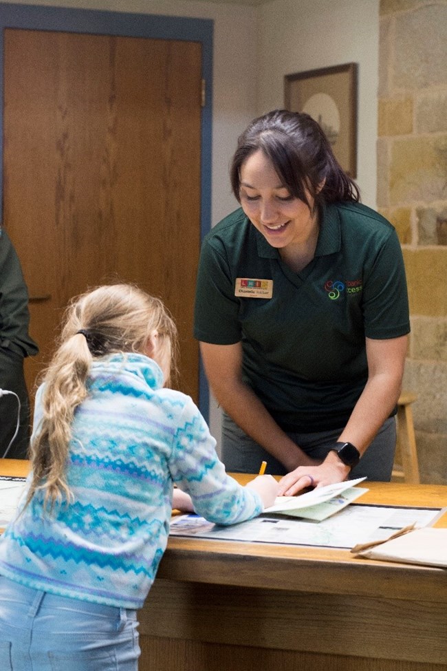 Two girls talking Female talking to a child about an activity book