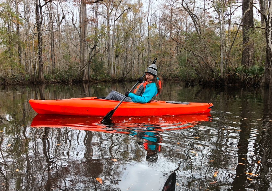 Kayaking A woman sits in an orange kayak on the water