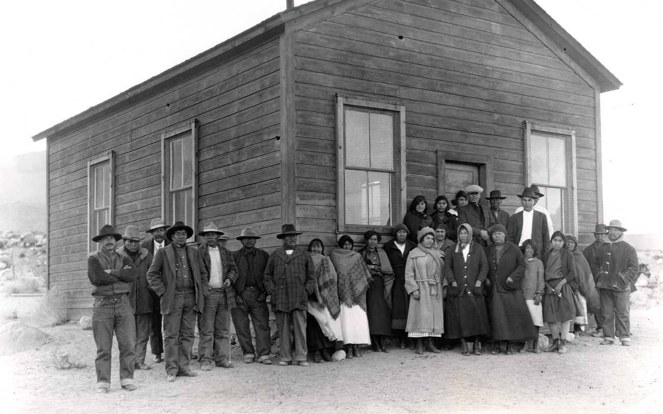 An old photo of Alice Piper with a group of Owens Valley Paiute in front of the community center in the 1920s.