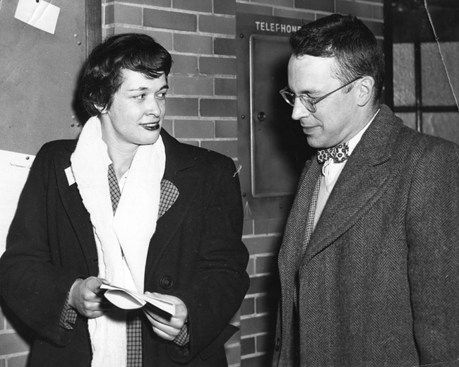 A black and white photo of Leona Woods Marshall Libby speaking to John Marshall on her left side.