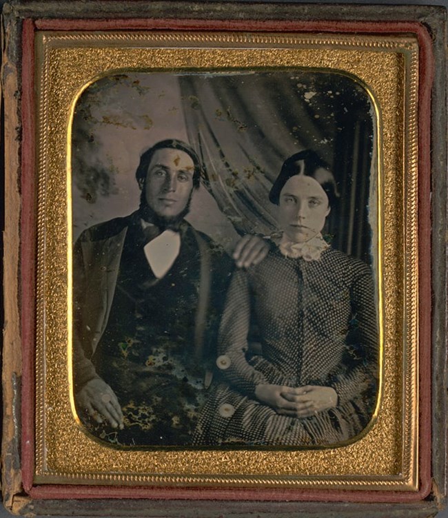 A faded portrait of William E. Randall (left) and Sarah Seaver Randall (right), sitting down and posing for a picture.