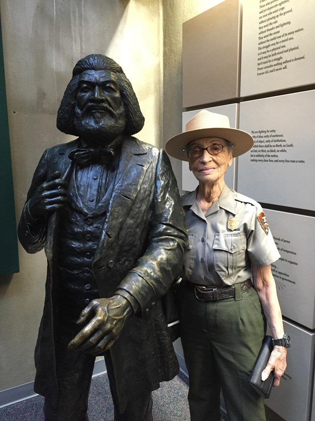 RORI_Betty Reid Soskin An image of Betty Reid Soskin posing for a picture next to a statue to her right.