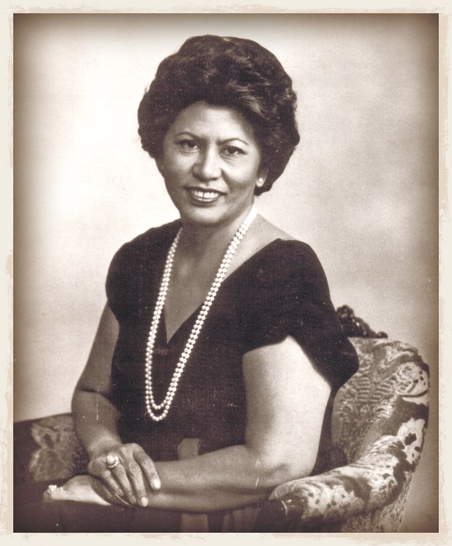An old photo of Cecilia Cruz Bamba sitting down in a chair and smiling for the camera.
