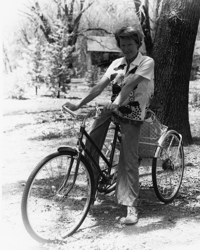 A black and white photo of Shirley Sargent on a bicycle.