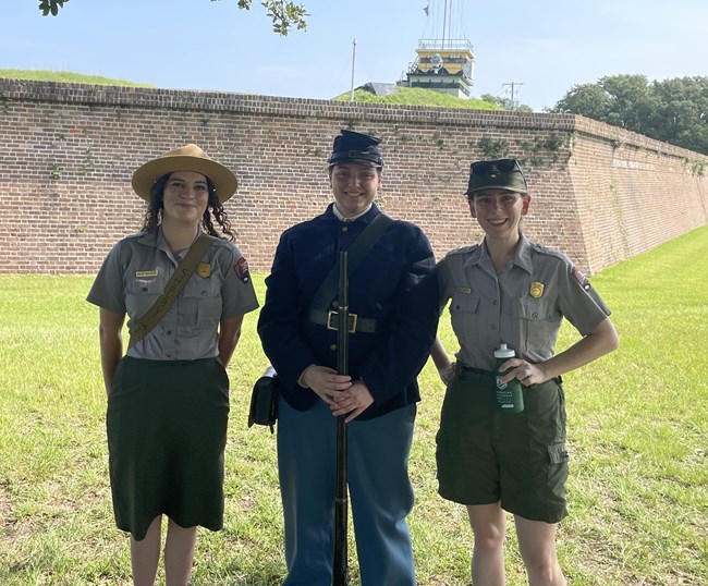 Rangers Two women dressed in park ranger uniforms stand with another women in a war uniform holding a musket