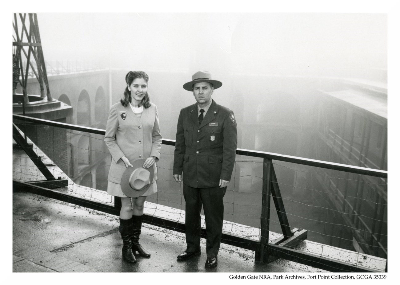 Two rangers stand on the third floor of Fort Point.