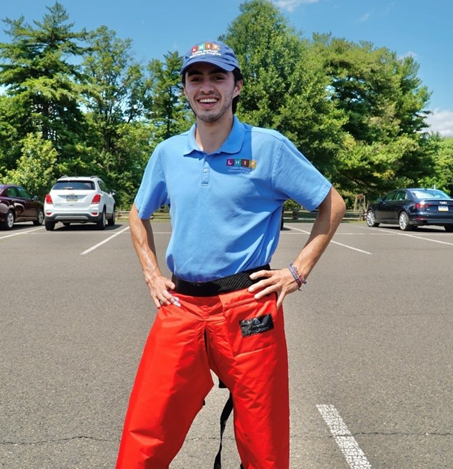 Andres Smiling A young man wearing a blue shirt with an "Latino Heritage Internship Program" smiling in a parking lot
