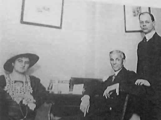 A woman and man sitting with another man standing