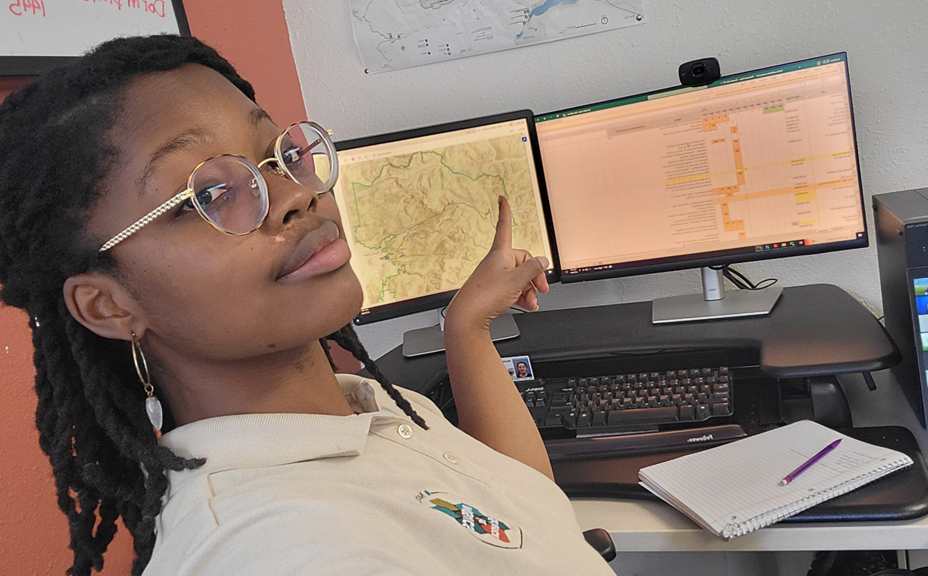 A young woman points at a computer screen with data on it