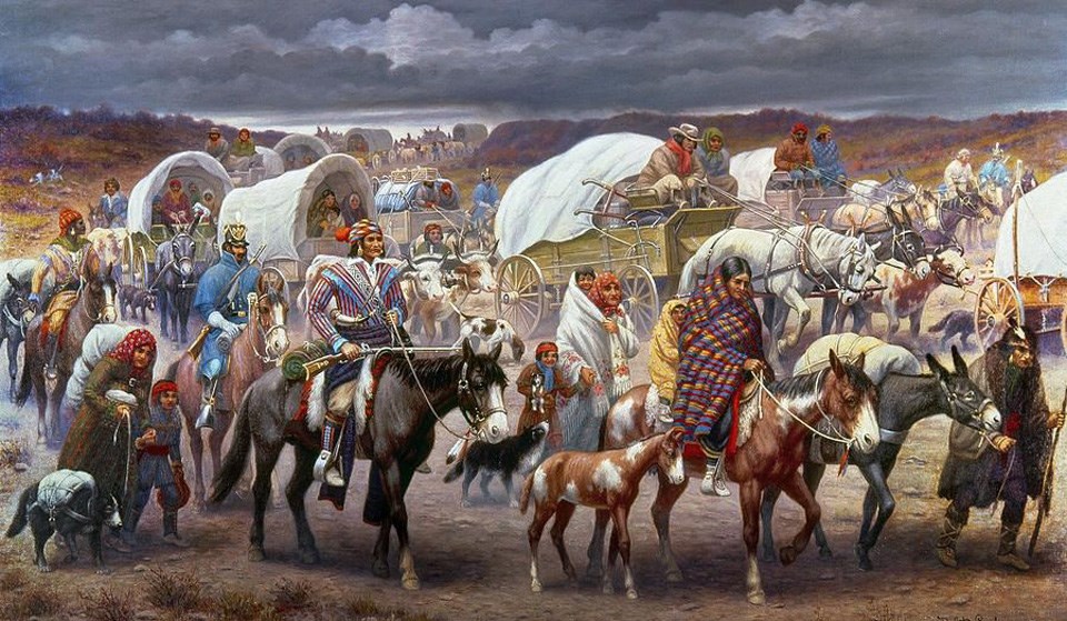 A large group of Indigenous peoples moving in a somberly across the landscape