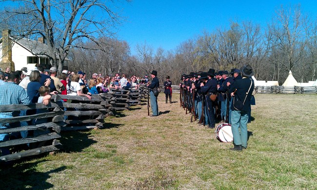 Photo of a large crowd of people watching a company of soldiers