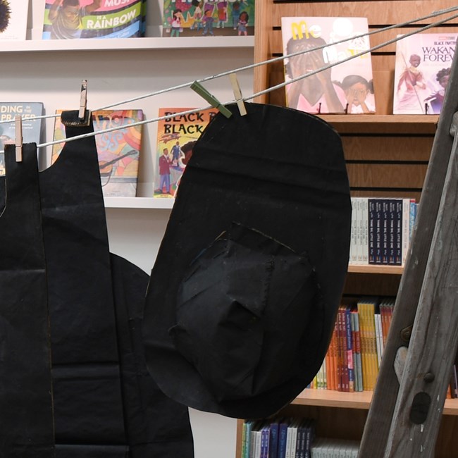 A black paper fisherman's hat hangs from a clothesline.