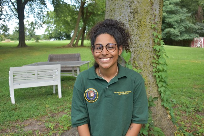 A black woman wearing a green NPS Volunteer polo shirt.