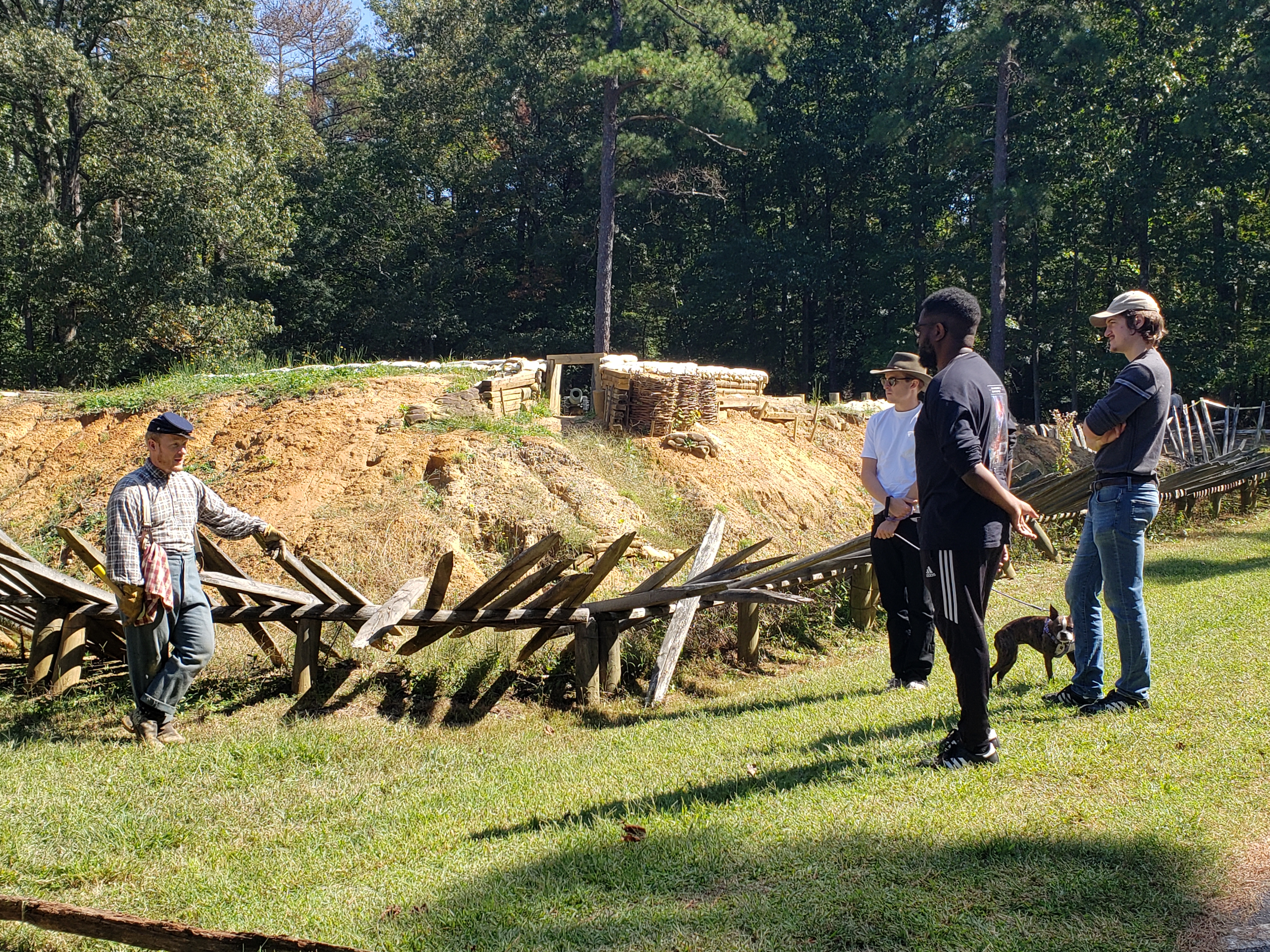 Living History Program at Stop 3 A white male in dressed as a Civil War soldier speaks to three people standing next to a reconstructed fortification.