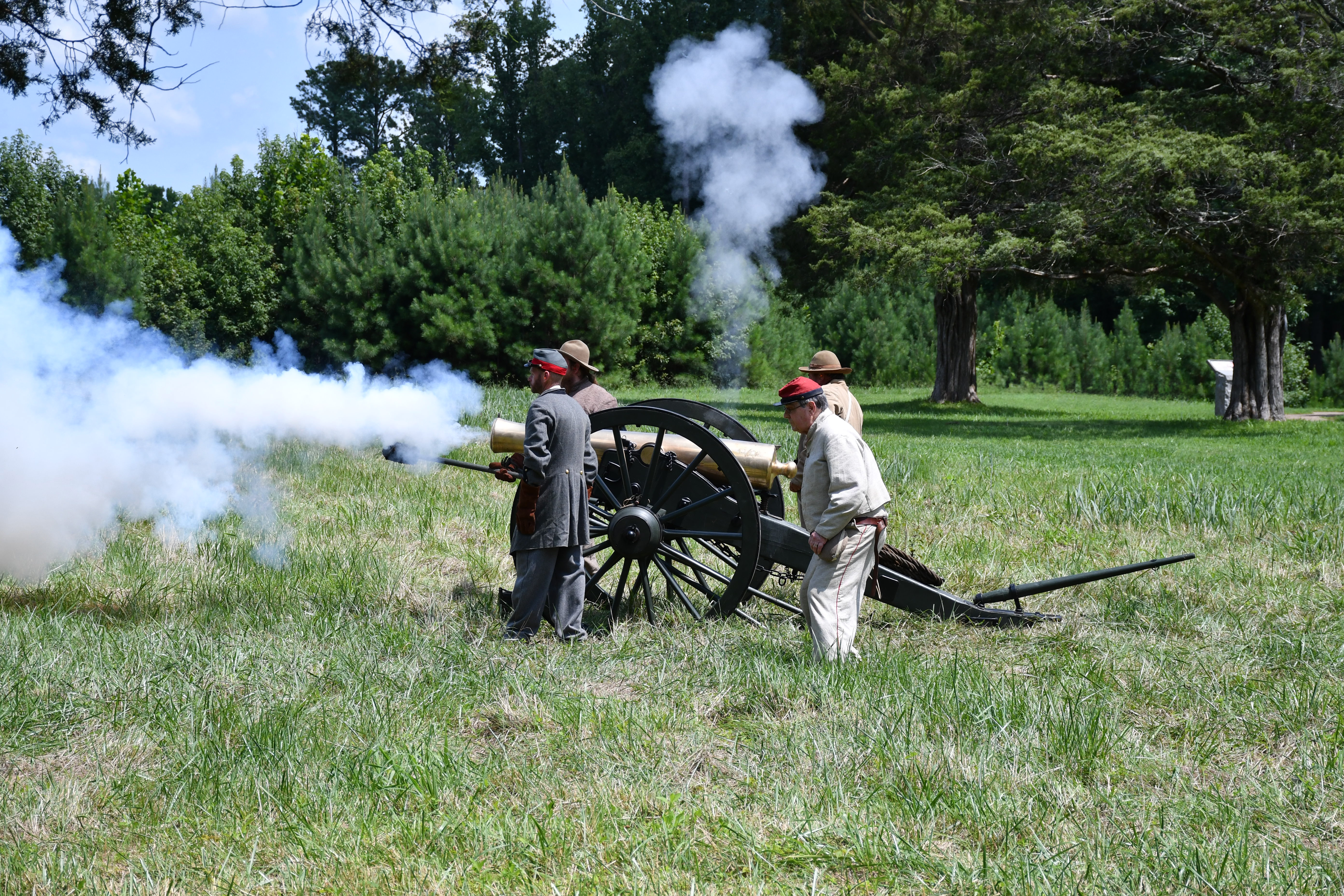 Living historians dressed in confederate uniforms demonstrate firing a cannon.