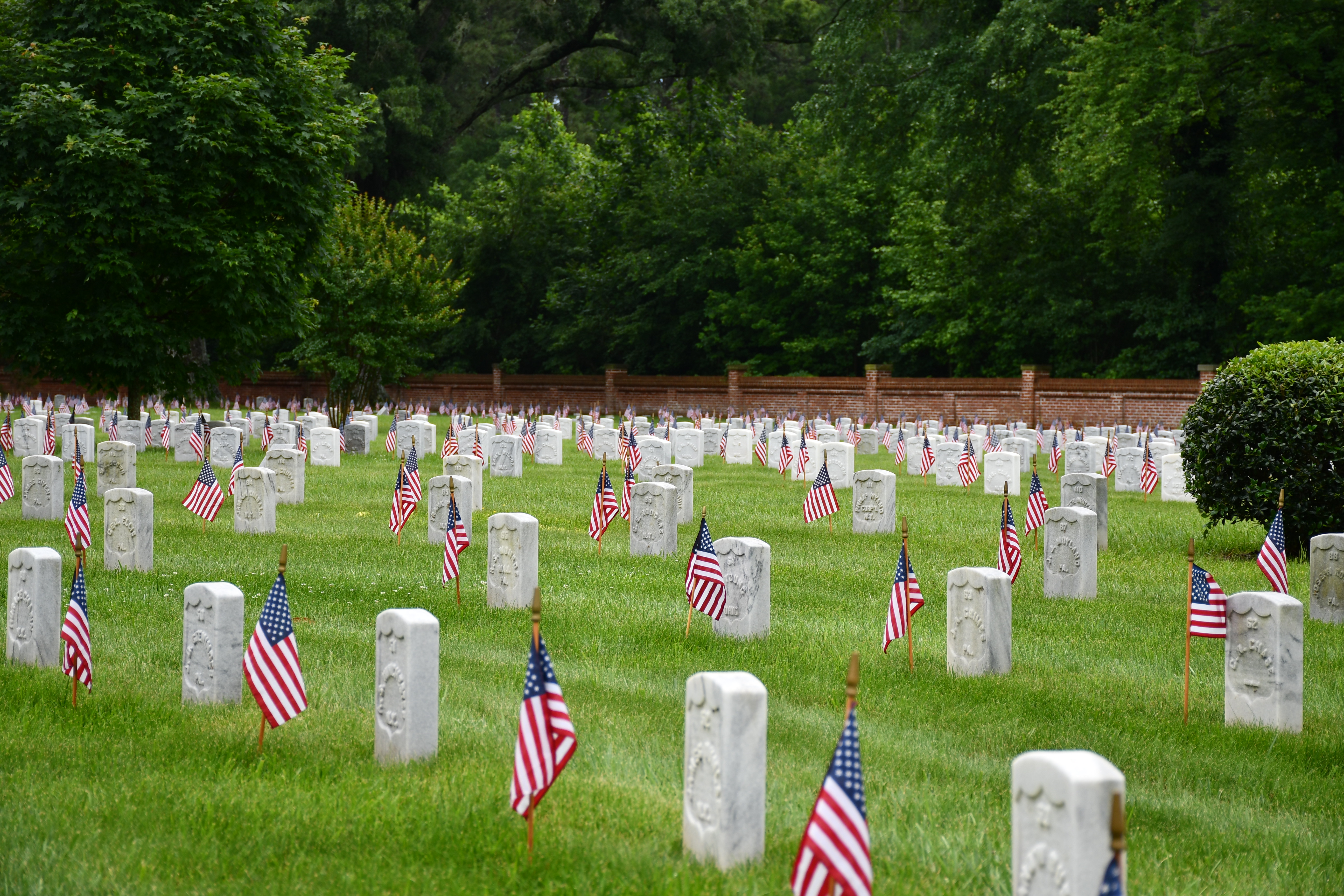Small U. S. flags in front of white headstones.