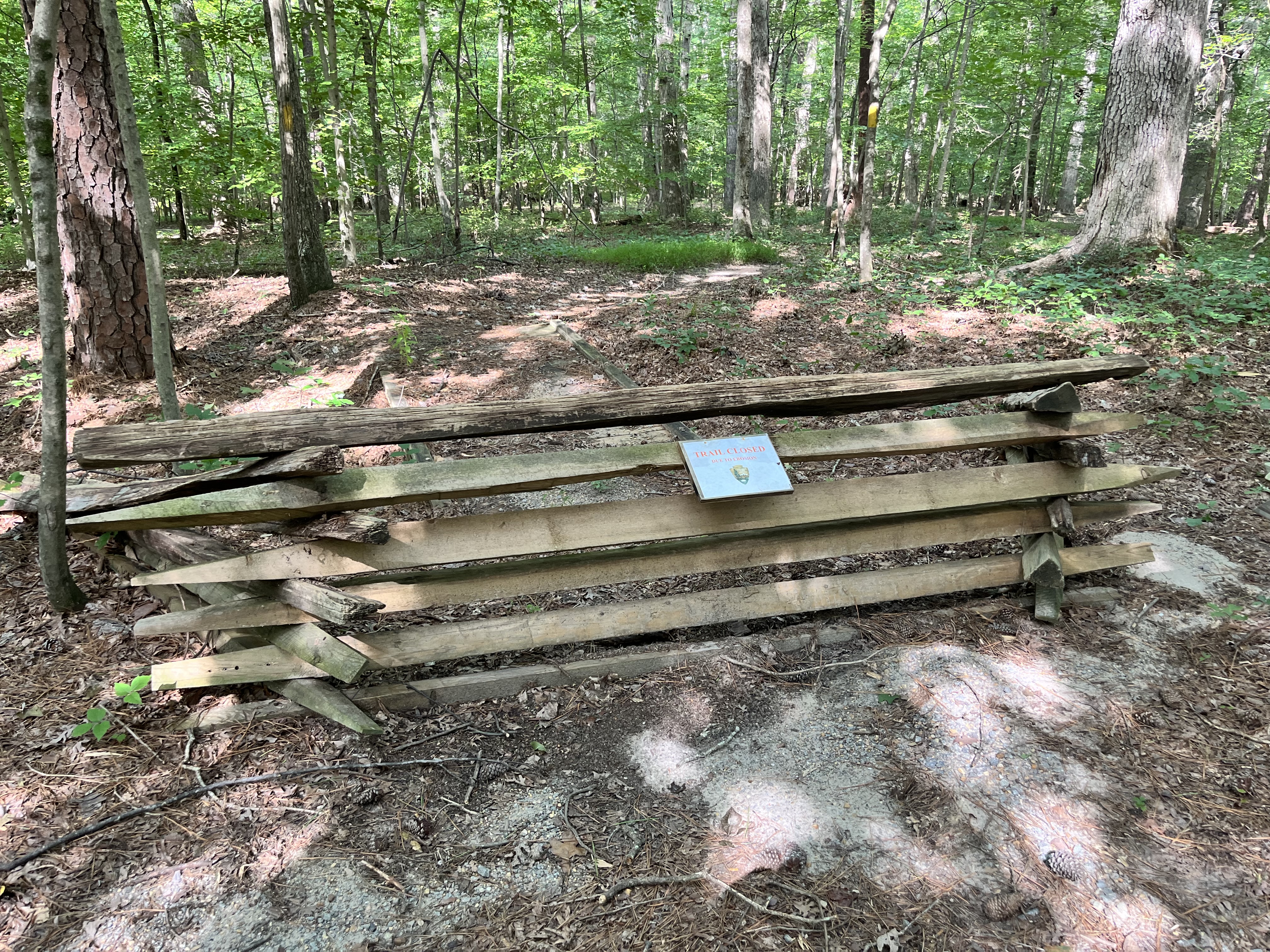 A split rail fence with a closed sign blocks a trail.