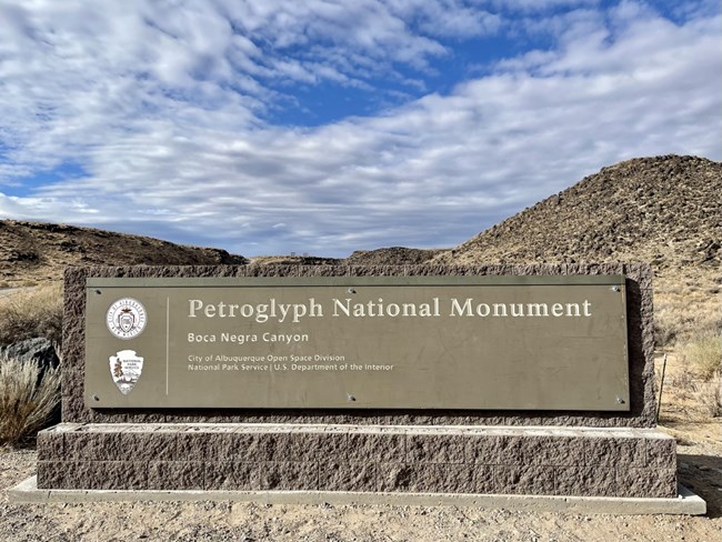 Sign for Boca Negra Canyon with the volcanic escarpment in the background.