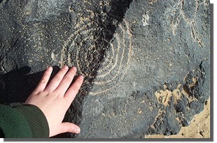 Persons hand touching a petroglyph