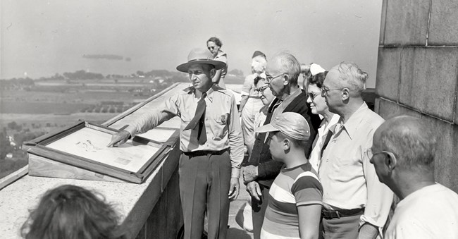 Ranger on observation deck telling the story of battle and the Lake Erie Islands to 8 visitors. Picture is black and white. Ranger on observation deck telling the story of battle and the Lake Erie Islands to 8 visitors. Picture is black and white.