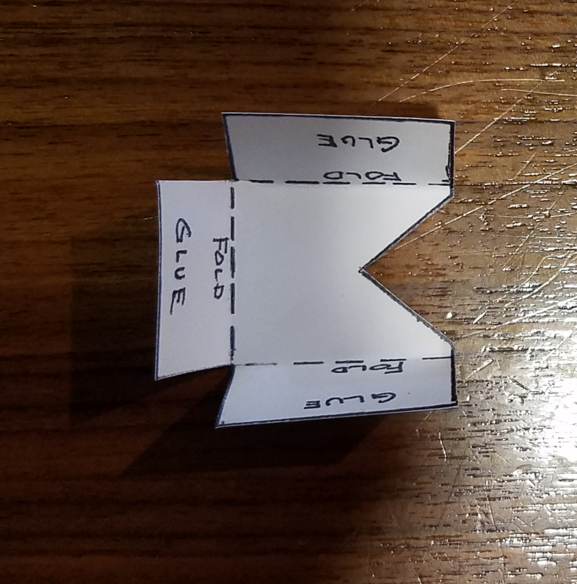 carriage support Small piece of paper with three folds along dotted lines. The piece of paper says fold and glue in three locations.