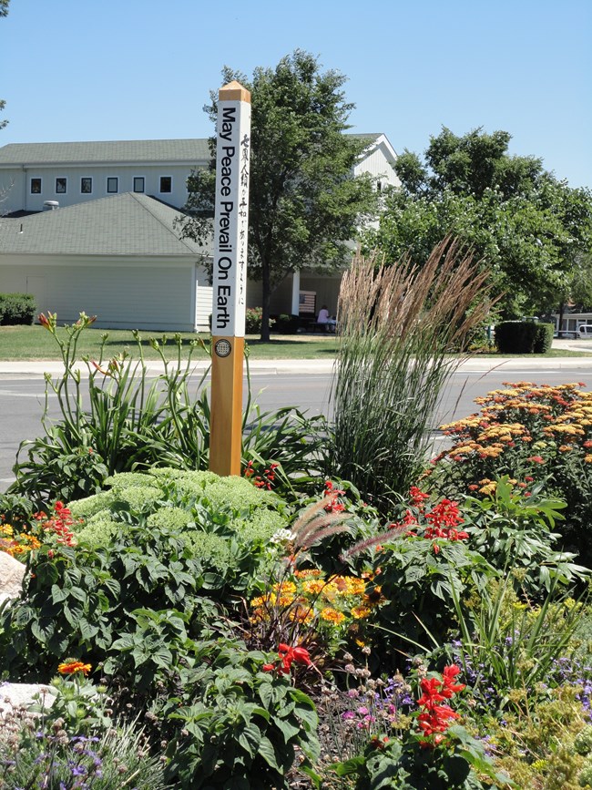 a post with peace garden shown in four different languages in the middle of a flower garden