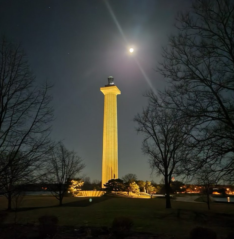 Memorial at night Tall stone memorial column light by large ground lights with a full moon over head.