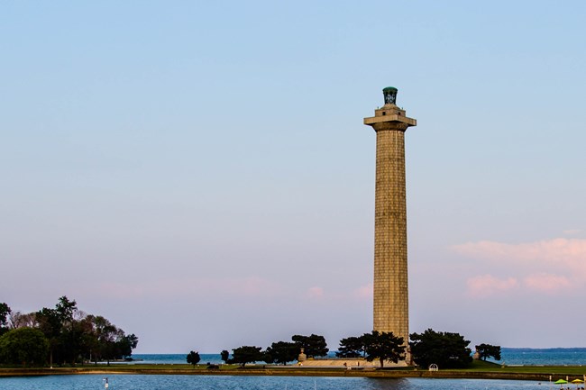 A pastel blue and pink sky behind Perry's Victory and International Memorial, a 352 foot tall marble column