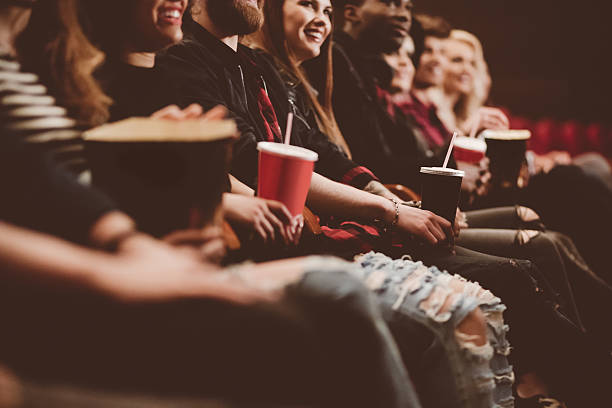 Row of people in a theater with popcorn and drinks.