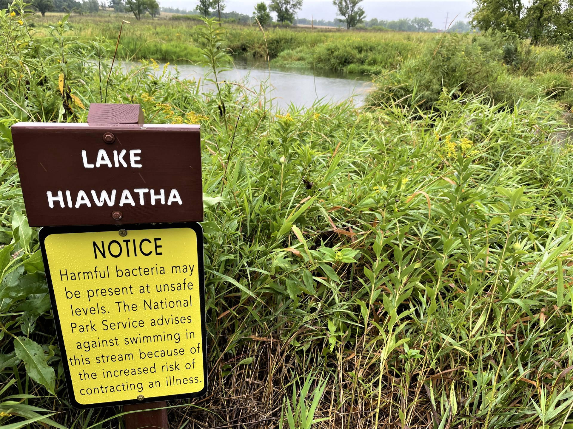 Yellow sign in grass next to a body of water